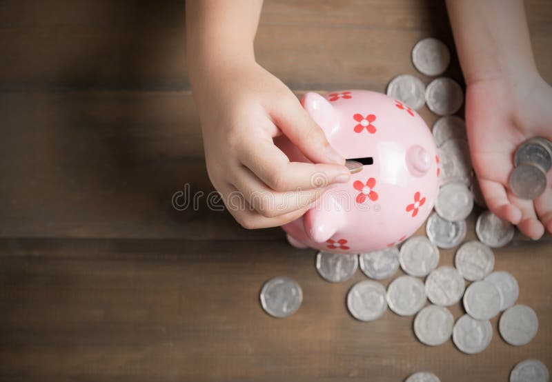 Τεθειμένο παιδί νόμισμα στη piggy τράπεζα στο εκλεκτής ποιότητας ξύλινο υπόβαθρο στοκ εικόνες Τεθειμένο παιδί νόμισμα στη piggy τράπεζα στο εκλεκτής ποιότητας ξύλινο υπόβαθρο στοκ εικόνες