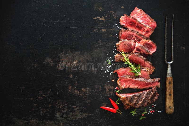 Sliced medium rare grilled beef ribeye steak on dark background. Sliced medium rare grilled beef ribeye steak on dark background