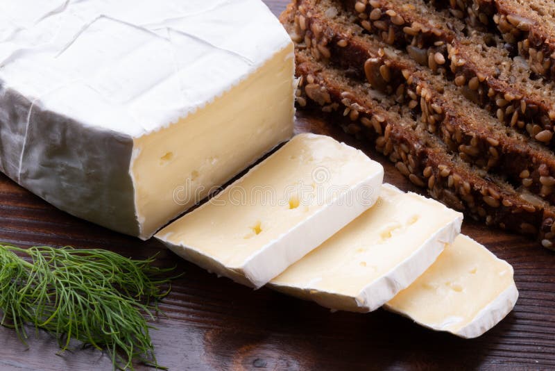 Τεμαχισμένο δύσοσμο camembert τυρί με το ψωμί σε έναν ξύλινο αγροτικό πίνακα στοκ φωτογραφία με δικαίωμα ελεύθερης χρήσης Τεμαχισμένο δύσοσμο camembert τυρί με το ψωμί σε έναν ξύλινο αγροτικό πίνακα στοκ φωτογραφία με δικαίωμα ελεύθερης χρήσης