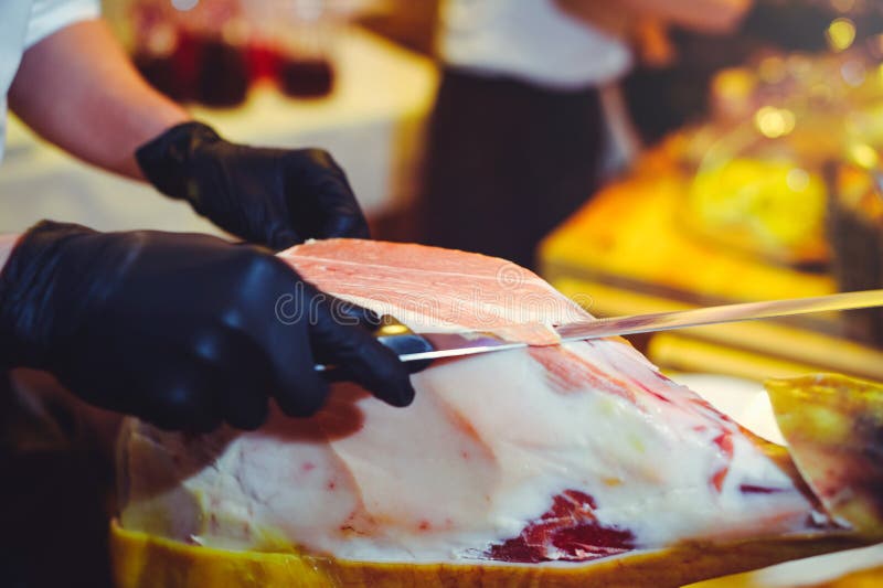 Τεμαχισμένο ξηρό prosciutto chamon Ένα άτομο κόβει ένα jamon, μια θερμή τονισμένη εικόνα Εκλεκτικό σημείο εστίασης στοκ εικόνα με δικαίωμα ελεύθερης χρήσης Τεμαχισμένο ξηρό prosciutto chamon Ένα άτομο κόβει ένα jamon, μια θερμή τονισμένη εικόνα Εκλεκτικό σημείο εστίασης στοκ εικόνα με δικαίωμα ελεύθερης χρήσης