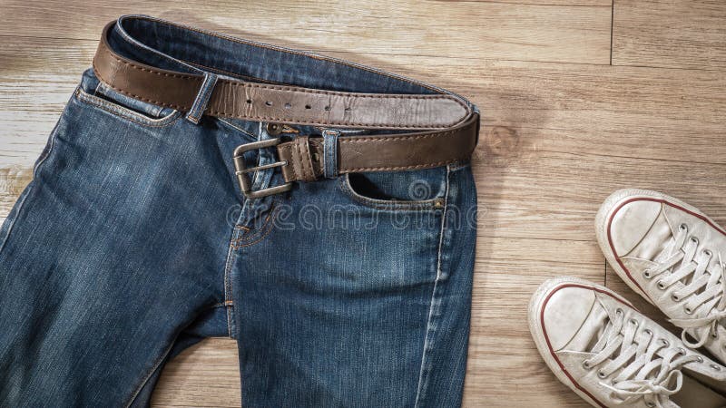 Τζιν παντελόνι με τη ζώνη δέρματος και βρώμικα άσπρα παπούτσια πάνινων παπουτσιών στο τ στοκ φωτογραφία με δικαίωμα ελεύθερης χρήσης Τζιν παντελόνι με τη ζώνη δέρματος και βρώμικα άσπρα παπούτσια πάνινων παπουτσιών στο τ στοκ φωτογραφία με δικαίωμα ελεύθερης χρήσης