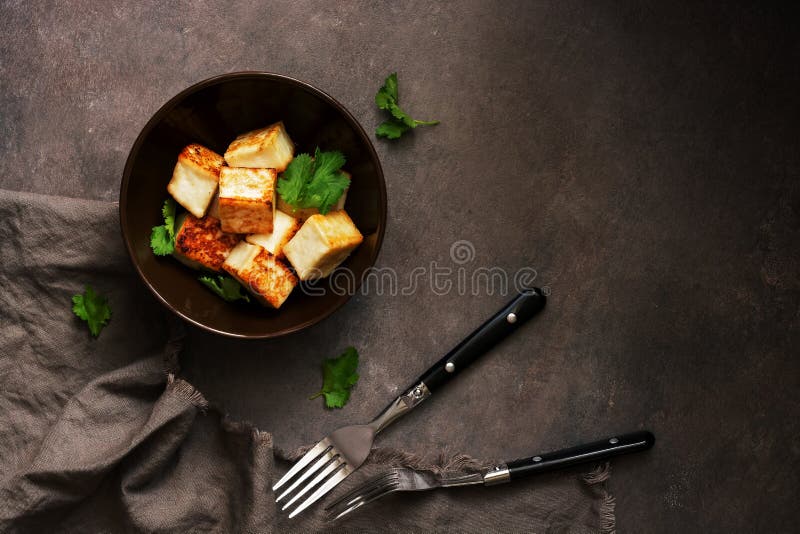 Τηγανισμένο tofu τυρί σε ένα κύπελλο με τα πράσινα σε ένα σκοτεινό υπόβαθρο E στοκ εικόνα με δικαίωμα ελεύθερης χρήσης Τηγανισμένο tofu τυρί σε ένα κύπελλο με τα πράσινα σε ένα σκοτεινό υπόβαθρο E στοκ εικόνα με δικαίωμα ελεύθερης χρήσης