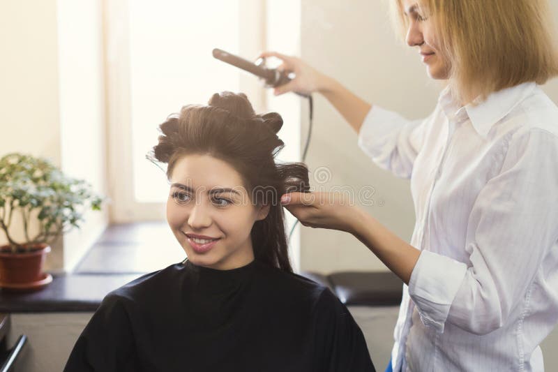 Το Hairstylist κάνει τις μπούκλες στην καφετιά τρίχα πελατών ` s στοκ φωτογραφία με δικαίωμα ελεύθερης χρήσης Το Hairstylist κάνει τις μπούκλες στην καφετιά τρίχα πελατών ` s στοκ φωτογραφία με δικαίωμα ελεύθερης χρήσης
