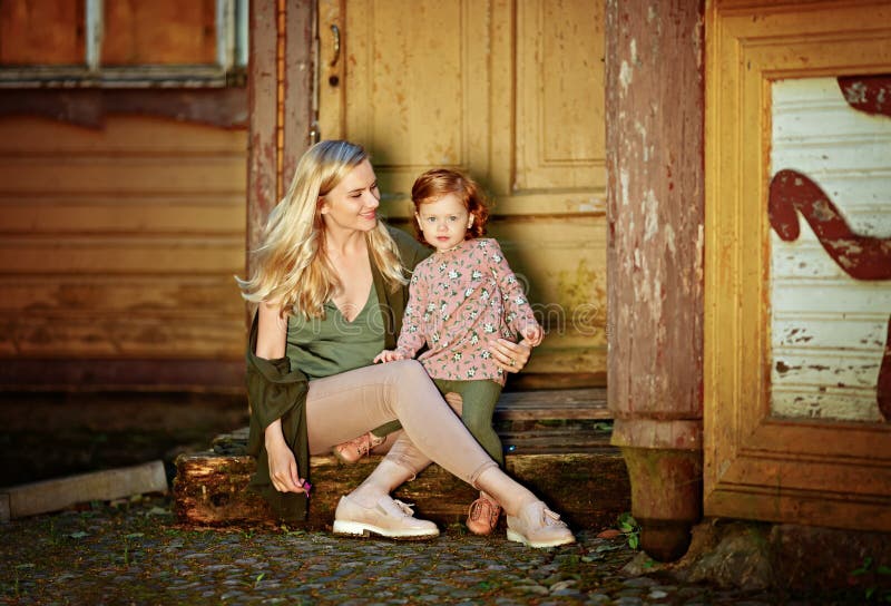 Το Mom και η κοκκινομάλλης κόρη κάθονται και χαμογελούν στα βήματα στοκ εικόνα