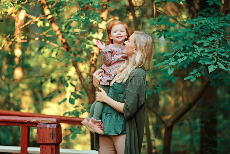 Το Mom και η κοκκινομάλλης κόρη κάθονται και χαμογελούν στο ηλιοβασίλεμα μέσα στοκ εικόνα