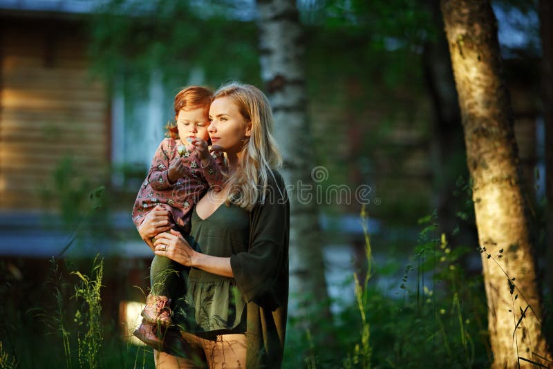 Το Mom και η κοκκινομάλλης κόρη κάθονται και χαμογελούν στο ηλιοβασίλεμα μέσα στοκ εικόνα με δικαίωμα ελεύθερης χρήσης