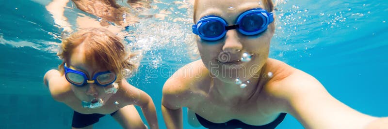 Το Mom και ο γιος στα γυαλιά κατάδυσης κολυμπούν στη λίμνη κάτω από το ΕΜΒΛΗΜΑ νερού, μακροχρόνιο σχήμα στοκ φωτογραφίες