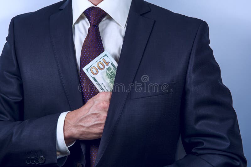 Το άτομο αφαιρεί τα αμερικανικά δολάρια στην τσέπη κοστουμιών του στοκ εικόνες Το άτομο αφαιρεί τα αμερικανικά δολάρια στην τσέπη κοστουμιών του στοκ εικόνες