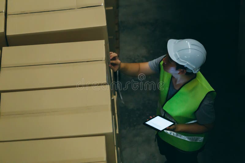 Το άτομο εργαζομένων αποθηκών εμπορευμάτων με το σκληρό καπέλο ασφάλειας ελέγχει τις λεπτομέρειες διαταγής με μια ψηφιακή ταμπλέτ στοκ φωτογραφίες με δικαίωμα ελεύθερης χρήσης Το άτομο εργαζομένων αποθηκών εμπορευμάτων με το σκληρό καπέλο ασφάλειας ελέγχει τις λεπτομέρειες διαταγής με μια ψηφιακή ταμπλέτ στοκ φωτογραφίες με δικαίωμα ελεύθερης χρήσης