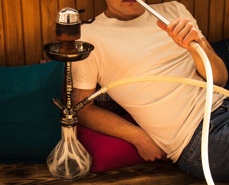 Το άτομο κάθεται και καπνίζει ένα hookah στοκ φωτογραφίες Το άτομο κάθεται και καπνίζει ένα hookah στοκ φωτογραφίες