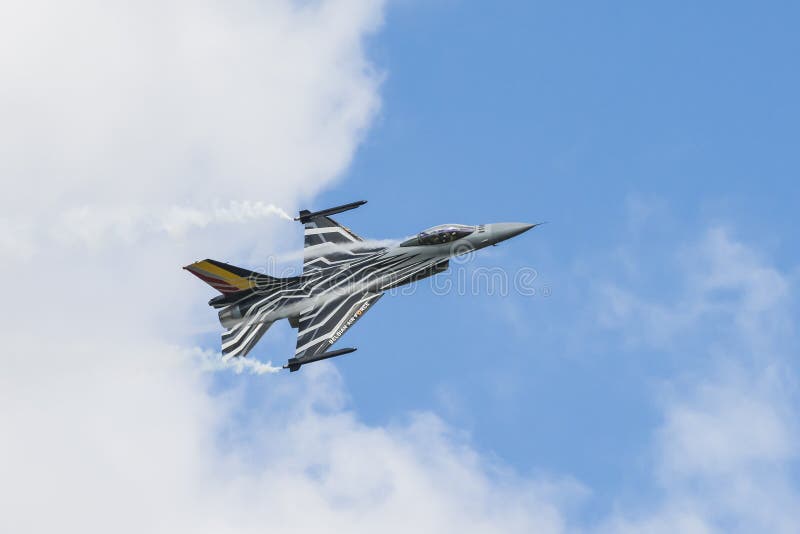Το βελγικό γεράκι πάλης F-16 με τον καπνό και συμπυκνώνει το ρεύμα στοκ φωτογραφία με δικαίωμα ελεύθερης χρήσης Το βελγικό γεράκι πάλης F-16 με τον καπνό και συμπυκνώνει το ρεύμα στοκ φωτογραφία με δικαίωμα ελεύθερης χρήσης
