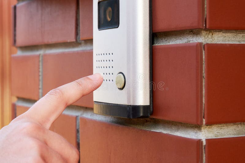 Το θηλυκό χέρι πιέζει ένα κουμπί doorbell με την ενδοσυνεννόηση στοκ εικόνες Το θηλυκό χέρι πιέζει ένα κουμπί doorbell με την ενδοσυνεννόηση στοκ εικόνες