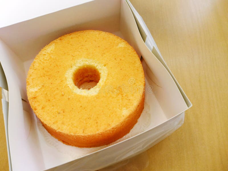 A photograph showing a newly baked citrus orange flavour chiffon style cake, soft and fluffy light dessert and tea item. Placed in take away box from bakery shop. Baked goods for takeout shopping concept. A photograph showing a newly baked citrus orange flavour chiffon style cake, soft and fluffy light dessert and tea item. Placed in take away box from bakery shop. Baked goods for takeout shopping concept.