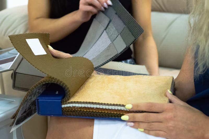 Το κορίτσι βλέπει τα δείγματα του υφάσματος για τα έπιπλα στο σπίτι ή το εμπορικό κτήριο Μεγάλος κατάλογος χρώματος του υφάσματος στοκ εικόνα Το κορίτσι βλέπει τα δείγματα του υφάσματος για τα έπιπλα στο σπίτι ή το εμπορικό κτήριο Μεγάλος κατάλογος χρώματος του υφάσματος στοκ εικόνα