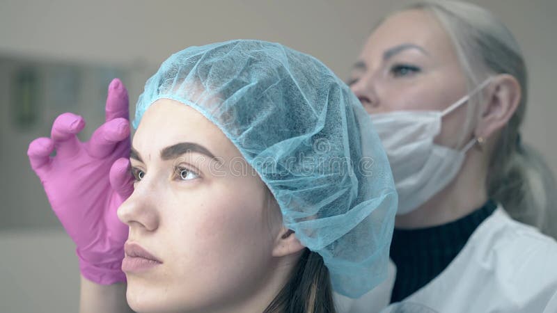 Το κορίτσι και το cosmetologist εξετάζουν τα brows με το μόνιμο makeup