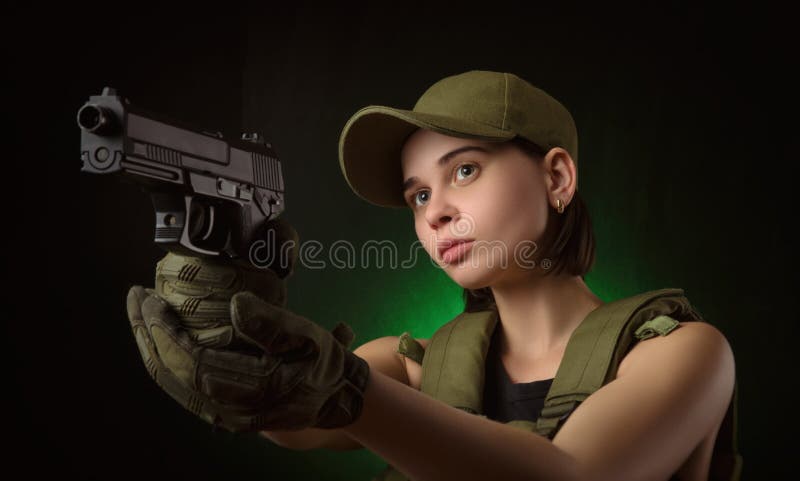 Girl in military special clothes posing with a gun in his hands on a dark background in the haze. Girl in military special clothes posing with a gun in his hands on a dark background in the haze