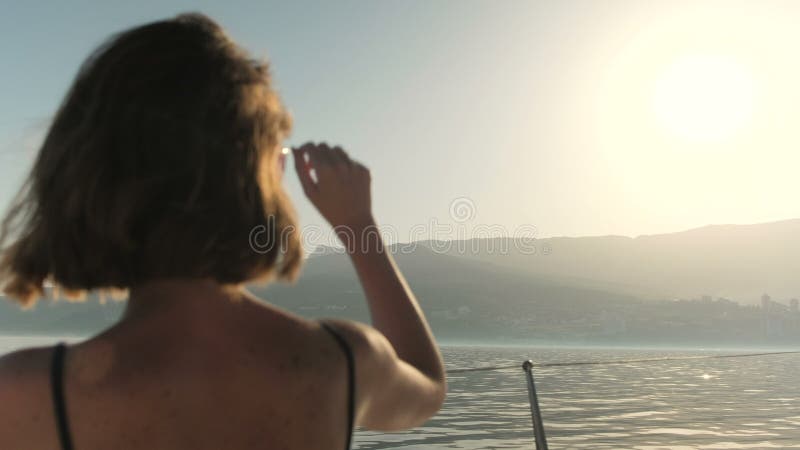 Το κορίτσι με την κοντή τρίχα και sunlasses εξετάζει τη θάλασσα