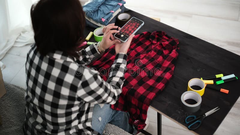 Το Κορίτσι Τραβάει Φωτογραφίες Με Smartphone Για Πώληση Μπλουζιών Μέσω Διαδικτύου απόθεμα βίντεο