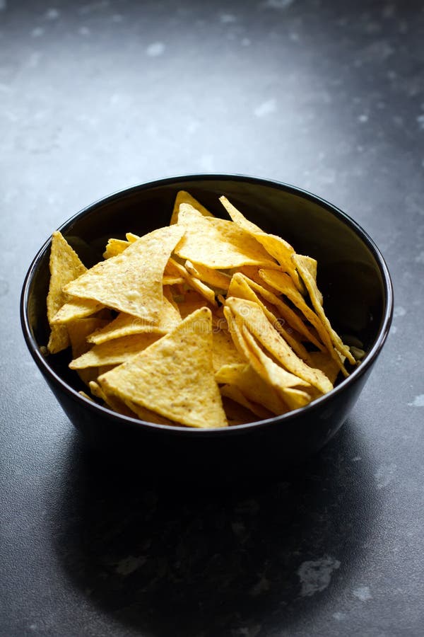 Bowl of tortilla chips on a black kitchen counter. Bowl of tortilla chips on a black kitchen counter