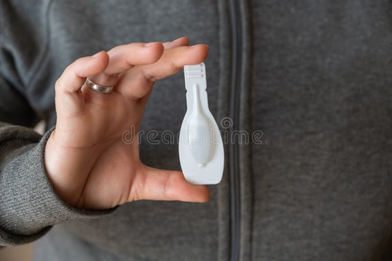 The middle section of the woman`s holding the flea tick spot-on. White sealed package with a veterinary drug for pets.  Close-up. Selective focus. The middle section of the woman`s holding the flea tick spot-on. White sealed package with a veterinary drug for pets.  Close-up. Selective focus.