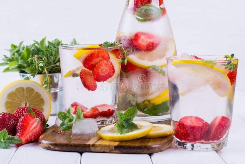 Mineral infused water with strawberry, ice, herb and mint leaves on white background, homemade detox soda water recipe. Mineral infused water with strawberry, ice, herb and mint leaves on white background, homemade detox soda water recipe.