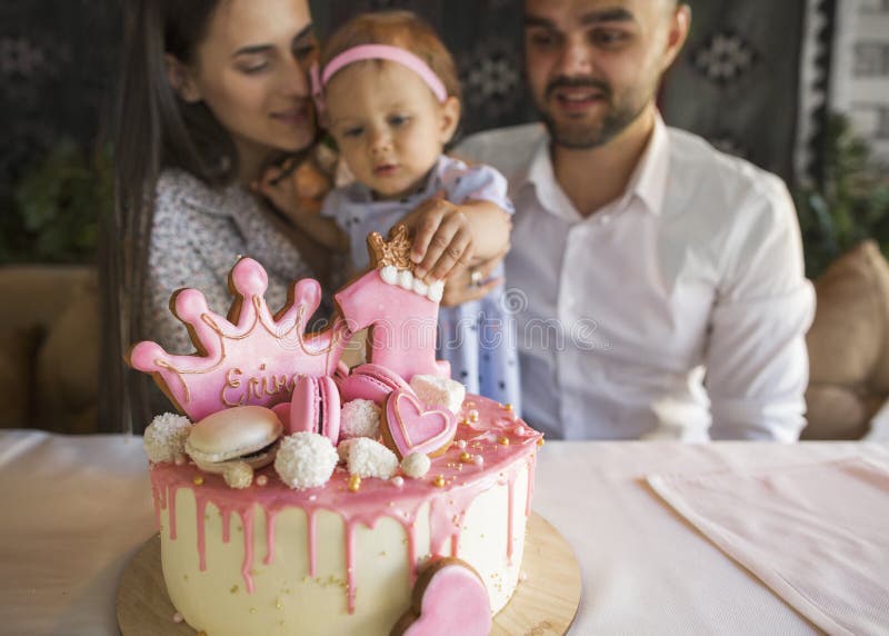 Το μικρό κορίτσι με μια οικογένεια στα γενέθλιά της εξετάζει ένα ασβέστιο γενεθλίων στοκ εικόνες Το μικρό κορίτσι με μια οικογένεια στα γενέθλιά της εξετάζει ένα ασβέστιο γενεθλίων στοκ εικόνες