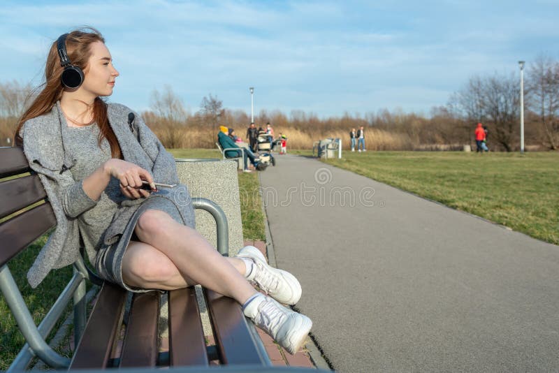 Το νέο, ευτυχές redhead κορίτσι την άνοιξη στο πάρκο κοντά στον ποταμό ακούει τη μουσική μέσω των ασύρματων ακουστικών bluetooth στοκ φωτογραφία Το νέο, ευτυχές redhead κορίτσι την άνοιξη στο πάρκο κοντά στον ποταμό ακούει τη μουσική μέσω των ασύρματων ακουστικών bluetooth στοκ φωτογραφία