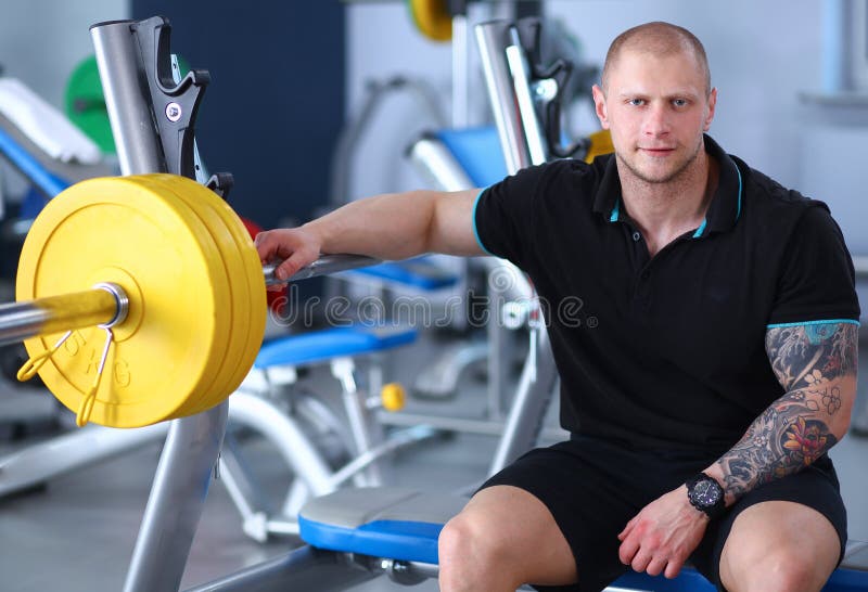 Το νέο όμορφο άτομο κάθεται μετά από το workout στη γυμναστική στοκ φωτογραφίες Το νέο όμορφο άτομο κάθεται μετά από το workout στη γυμναστική στοκ φωτογραφίες