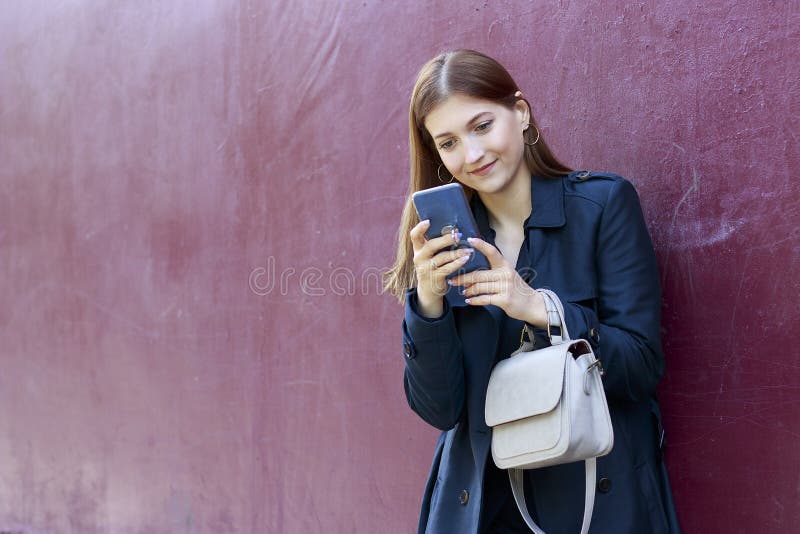 Το νέο όμορφο κορίτσι εξετάζει το smartphone, ρόδινο υπόβαθρο στοκ εικόνες Το νέο όμορφο κορίτσι εξετάζει το smartphone, ρόδινο υπόβαθρο στοκ εικόνες