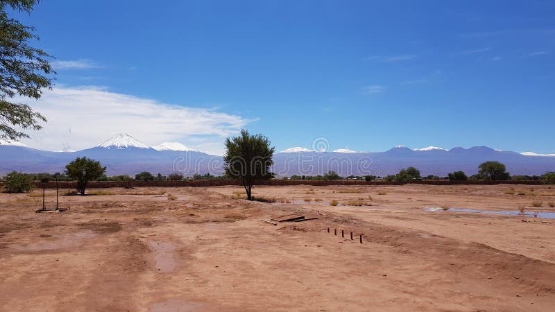 Το ξηρό και έρημο τοπίο της ερήμου Atacama με τις αιχμές των χιονωδών ηφαιστείων της οροσειράς των Άνδεων στοκ εικόνα Το ξηρό και έρημο τοπίο της ερήμου Atacama με τις αιχμές των χιονωδών ηφαιστείων της οροσειράς των Άνδεων στοκ εικόνα