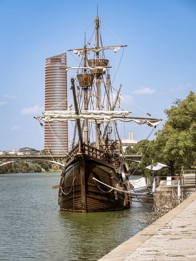 The Nao Victoria replica carrack ship docked at the Guadalquivir River in the historic central downtown area of Seville, Spain, sunset golden hour. The Nao Victoria replica carrack ship docked at the Guadalquivir River in the historic central downtown area of Seville, Spain, sunset golden hour