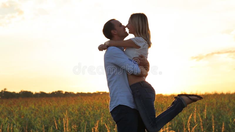 Το ρομαντικό νέο ζεύγος φιλά σε ένα ηλιοβασίλεμα με να λάμψει ήλιων φωτεινό πίσω