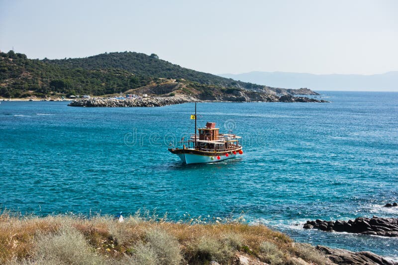 Το σκάφος πλέει στο μικρό λιμάνι Sarti, τοποθετεί Athos στο υπόβαθρο, Sithonia στοκ εικόνα Το σκάφος πλέει στο μικρό λιμάνι Sarti, τοποθετεί Athos στο υπόβαθρο, Sithonia στοκ εικόνα
