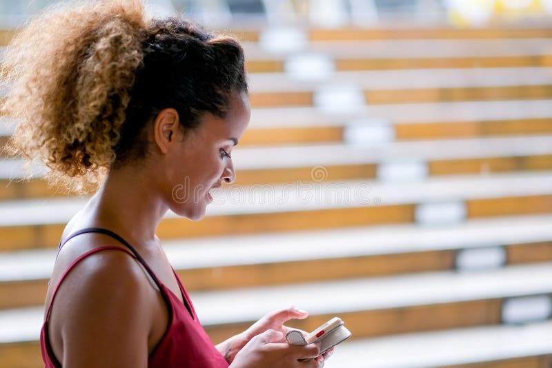 Το σκοτεινό δέρμα μαυρίσματος ανάμιξε τη λαβή γυναικών φυλών το κινητό τηλέφωνό της και στέκεται επίσης τον τρόπο περιπάτων του τ στοκ εικόνες Το σκοτεινό δέρμα μαυρίσματος ανάμιξε τη λαβή γυναικών φυλών το κινητό τηλέφωνό της και στέκεται επίσης τον τρόπο περιπάτων του τ στοκ εικόνες