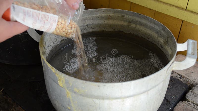 Το στενό χέρι χύνει στο μπιζέλι τη μεγάλη στάση δοχείων χάλυβα αναδρομική αγροτική σόμπα τούβλου φιλμ μικρού μήκους