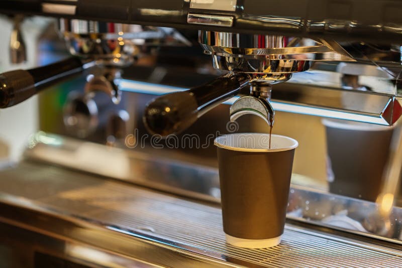 Close-up fresh espresso pours in paper cup, Italian espresso machine. Coffee culture and professional coffee making, service and catering concepts. Close-up fresh espresso pours in paper cup, Italian espresso machine. Coffee culture and professional coffee making, service and catering concepts