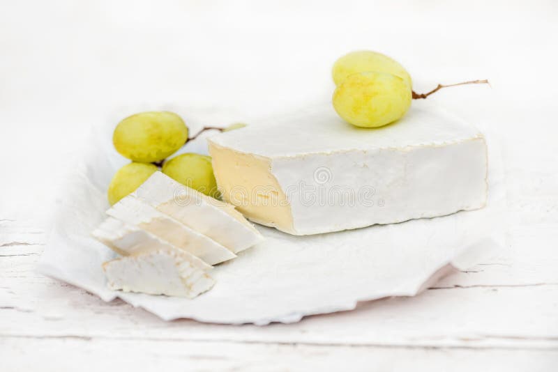 Το φρέσκο τυρί της Brie με τις φέτες και το σταφύλι άσπρο σε αγροτικό επιζητούν στοκ εικόνες με δικαίωμα ελεύθερης χρήσης Το φρέσκο τυρί της Brie με τις φέτες και το σταφύλι άσπρο σε αγροτικό επιζητούν στοκ εικόνες με δικαίωμα ελεύθερης χρήσης