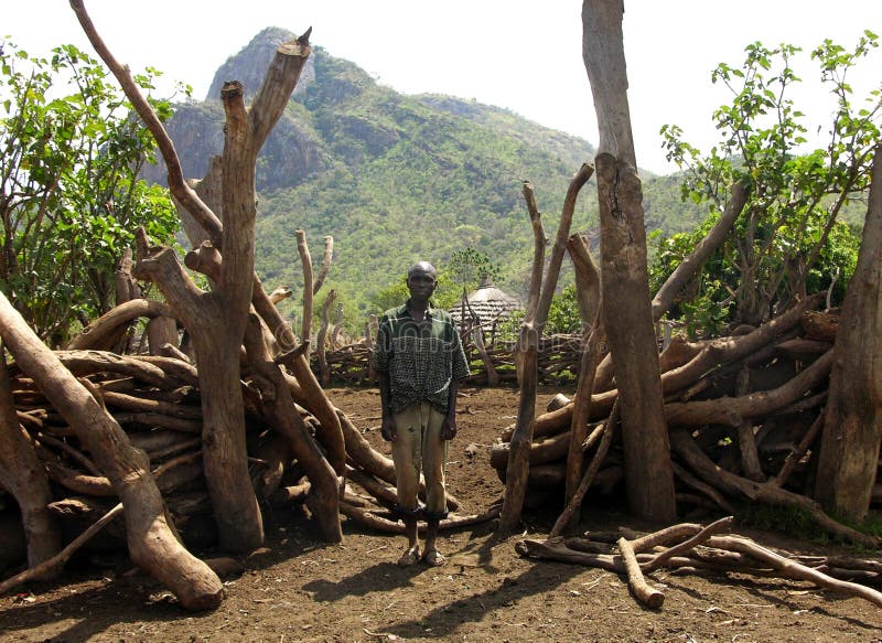 This image was taken in Karamoja, Uganda. A remote village of northern Uganda. This is an older farmer of the village whose job it is to look after any livestock and animals they may have. He took me by the hand to show me his hand built corral enclosure from tree logs and branches, to keep in their animals. He gladly posed, standing proudly showing off his very hard work. This image was taken in Karamoja, Uganda. A remote village of northern Uganda. This is an older farmer of the village whose job it is to look after any livestock and animals they may have. He took me by the hand to show me his hand built corral enclosure from tree logs and branches, to keep in their animals. He gladly posed, standing proudly showing off his very hard work.