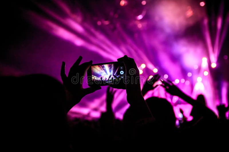 Το χέρι με ένα smartphone καταγράφει το φεστιβάλ ζωντανής μουσικής, που παίρνει τη φωτογραφία της σκηνής συναυλίας στοκ εικόνα με δικαίωμα ελεύθερης χρήσης Το χέρι με ένα smartphone καταγράφει το φεστιβάλ ζωντανής μουσικής, που παίρνει τη φωτογραφία της σκηνής συναυλίας στοκ εικόνα με δικαίωμα ελεύθερης χρήσης