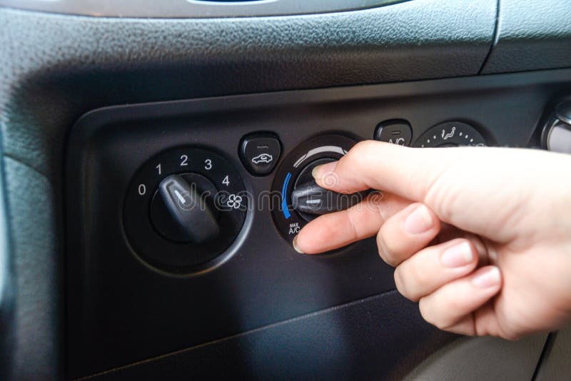 Woman`s hand turning on knobs of car air conditioning system. Woman`s hand turning on knobs of car air conditioning system