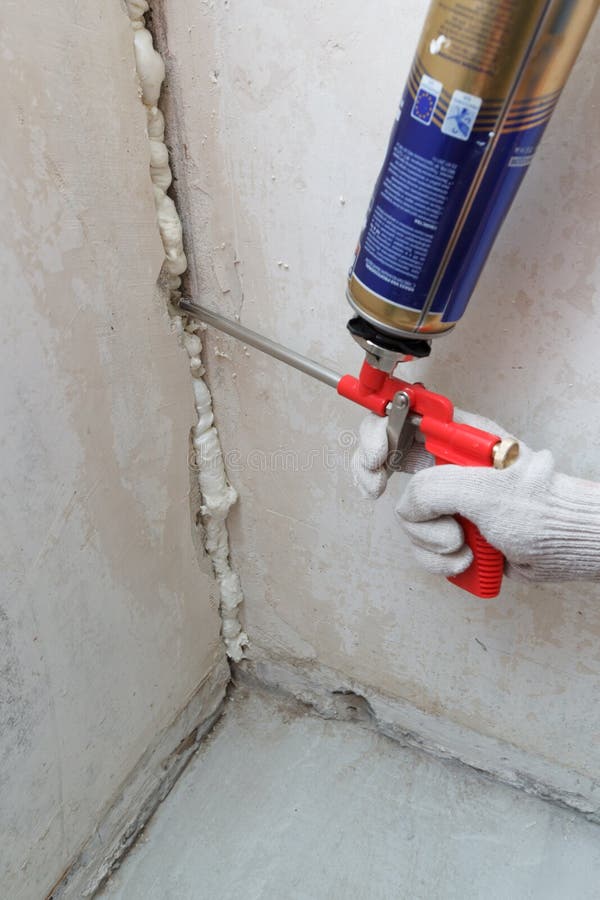 Worker's hand fix a rent in wall using polyurethane foam, view 1. Worker's hand fix a rent in wall using polyurethane foam, view 1