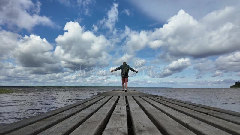 Το χρονοδιάγραμμα δείχνει έναν άντρα σε μια ξύλινη προβλήτα δίπλα σε μια λίμνη με σύννεφα να αιωρούνται στον ουρανό σε μια απόθεμα βίντεο