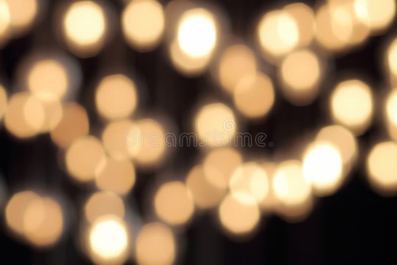 Το χρυσό bokeh σε ένα μαύρο υπόβαθρο, αφαιρεί το σκοτεινό σκηνικό με τα θερμά φω'τα στοκ εικόνες