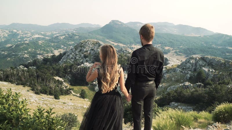 Το όμορφο αγάπης πρότυπο γυναικών ζευγών νέο σε ένα έξυπνο μακρύ φόρεμα και ένας άνδρας στο Μαύρο ταιριάζουν την τοποθέτηση στη κ απόθεμα βίντεο