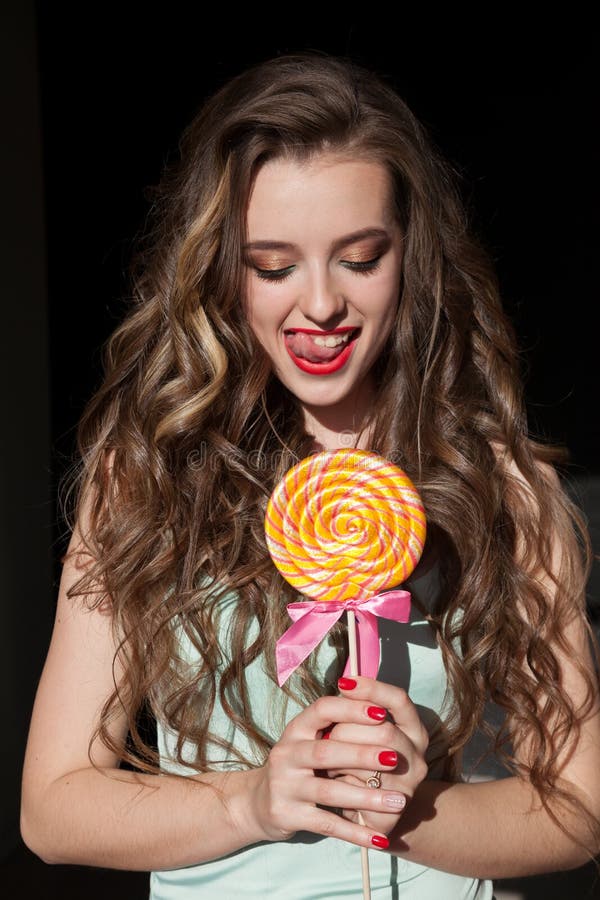 Το όμορφο κορίτσι τρώει ένα μεγάλο γλυκό lollipop στοκ φωτογραφίες με δικαίωμα ελεύθερης χρήσης Το όμορφο κορίτσι τρώει ένα μεγάλο γλυκό lollipop στοκ φωτογραφίες με δικαίωμα ελεύθερης χρήσης