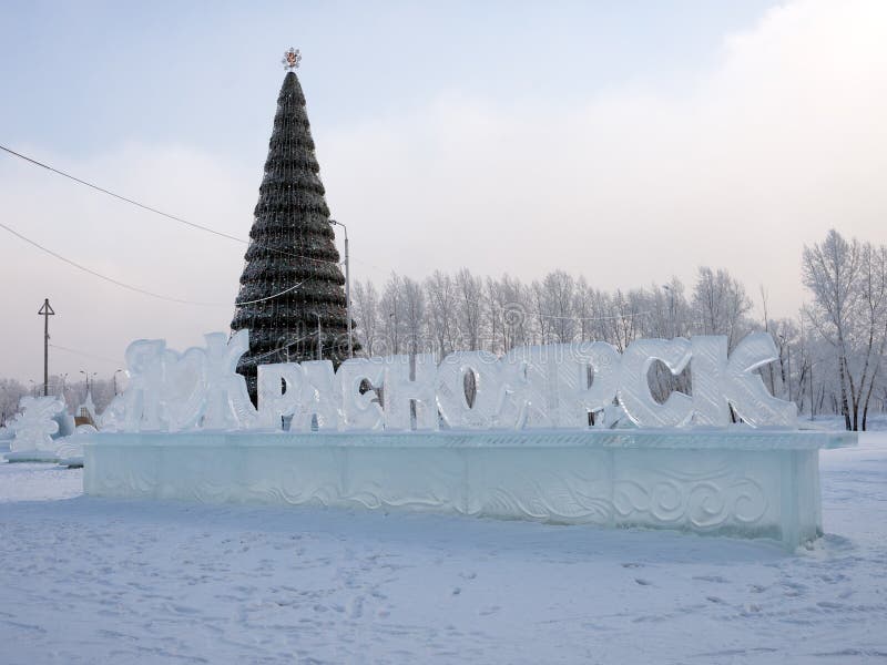 το όνομα της πόλης στα ρωσικά σκαλισμένα από πάγο στέκεται στο φόντο ενός χριστουγεννιάτικου δέντρου διακοσμημένου.