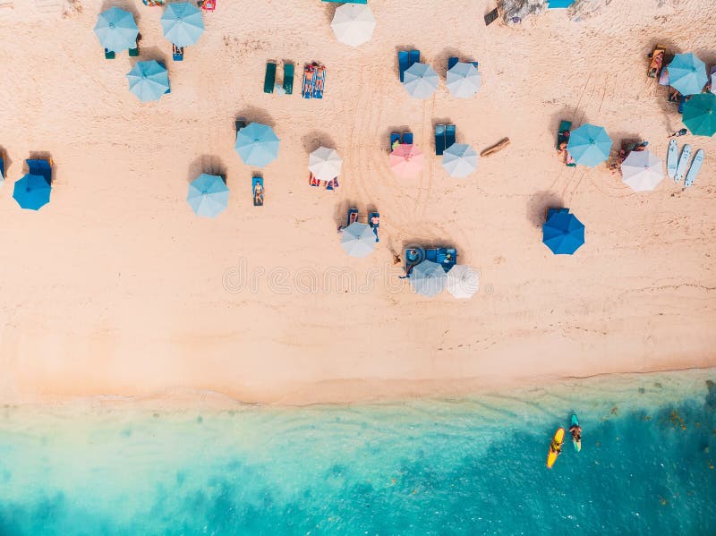 Τοπ άποψη της αμμώδους παραλίας με το τυρκουάζ θαλάσσιο νερό και τις ζωηρόχρωμες μπλε ομπρέλες, εναέριος πυροβολισμός κηφήνων