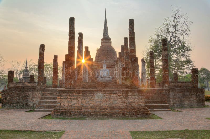 Sunset scenery of Wat Sa Si in Sukhothai Historical Park with setting sun in background and a statue of seated Buddha in the shrine of a ruined temple ~ A beautiful UNESCO heritage site in Thailand. Sunset scenery of Wat Sa Si in Sukhothai Historical Park with setting sun in background and a statue of seated Buddha in the shrine of a ruined temple ~ A beautiful UNESCO heritage site in Thailand