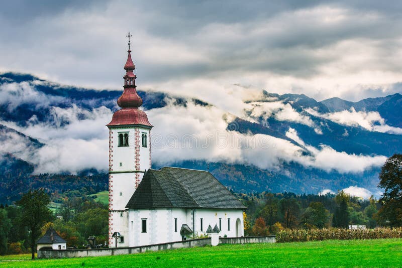 Τοπίο της Σλοβενίας πλησίον Λίμνη Bohinj Εικονικός σλοβένικος ναός με τα όμορφα ομιχλώδη βουνά στο υπόβαθρο στοκ εικόνες με δικαίωμα ελεύθερης χρήσης Τοπίο της Σλοβενίας πλησίον Λίμνη Bohinj Εικονικός σλοβένικος ναός με τα όμορφα ομιχλώδη βουνά στο υπόβαθρο στοκ εικόνες με δικαίωμα ελεύθερης χρήσης
