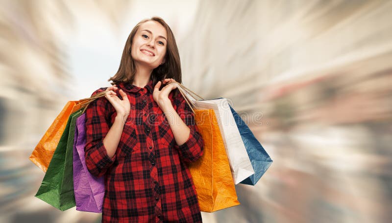 τοποθετεί τις shoping νεολαί&epsi. Πώληση Ευτυχής νέα γυναίκα με οι τσάντες στο θολωμένο υπόβαθρο οδών πόλεων